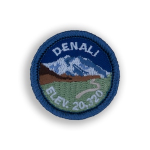 May include: A blue and white embroidered patch with the text "DENALI Elev. 20,320" and a depiction of a mountain range.