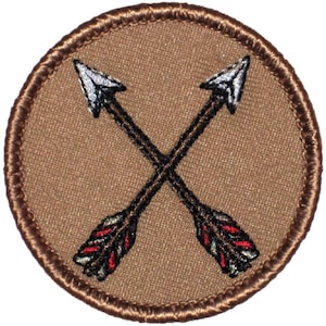 May include: A brown embroidered patch with two crossed arrows. The arrows are black with white fletching and red and white feathers.