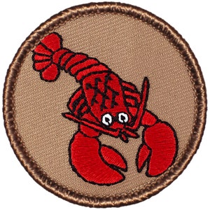 May include: A red embroidered lobster patch with black outlines on a brown background. The lobster has a cartoon-like appearance with large eyes and a smiling mouth.