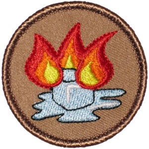 May include: A brown embroidered patch with a blue and white campfire design. The campfire is on fire with three orange and yellow flames.