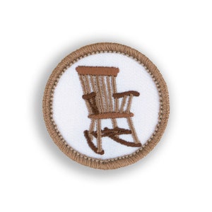 May include: A brown embroidered patch with a rocking chair on a white background. The patch is surrounded by a brown stitched border.