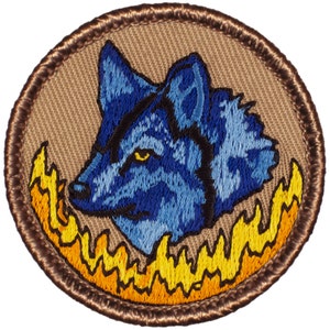 May include: A blue wolf head embroidered patch with a yellow and orange flame design around the head. The patch is surrounded by a brown stitched border.