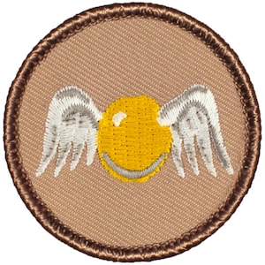 May include: A brown embroidered patch with a golden snitch with white wings. The snitch is a round, yellow object with a small, silver smile.
