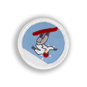 May include: A white embroidered patch with a blue background depicting a person snowboarding upside down. The person is wearing a white jacket, gray pants, and a red helmet. The snowboard is red.