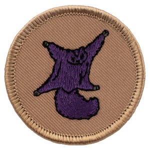 May include: A purple embroidered patch of a flying squirrel with outstretched arms and legs, on a tan background with a brown stitched border.
