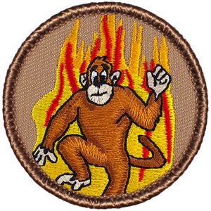 May include: Embroidered patch featuring a cartoon monkey in a brown and orange color scheme, running through a background of yellow and red flames. The monkey has a worried expression on its face.