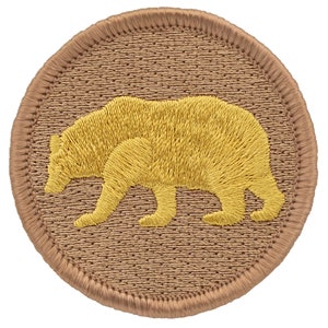 May include: A round, tan-colored patch with a yellow embroidered bear silhouette.