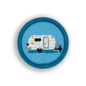 May include: A blue and white embroidered patch with a white camper on a blue background. The camper has a red taillight, yellow headlights, and a gray door.