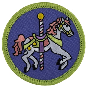 May include: A colorful embroidered patch featuring a white carousel horse with a pink mane and tail, a purple and green saddle, and a striped pole. The patch is surrounded by a green border.