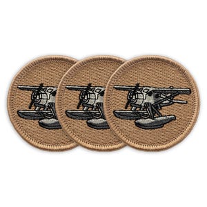 May include: Three brown embroidered patches with a white and black seaplane design. The seaplane has two floats.