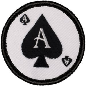 May include: A white embroidered patch with a black ace of spades playing card. The patch has a black border.