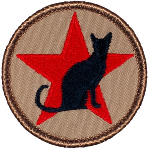 May include: A brown embroidered patch with a red star and a black cat silhouette. The patch has a brown border.