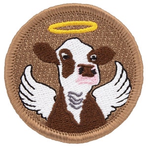 May include: Embroidered patch of a brown and white cow with a halo and wings. The patch is on a brown background.