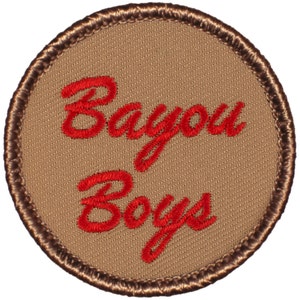 May include: A round, brown patch with a brown border. The text "Bayou Boys" is embroidered in red.