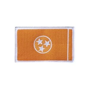 May include: Orange fabric patch with a white circle containing three white stars. The patch has a white border.