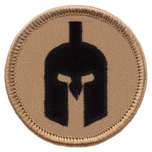 May include: A round, tan-colored patch with a black embroidered Spartan helmet design.