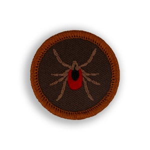 May include: A brown embroidered patch with a red and black tick on a dark brown background. The patch has a brown stitched border.