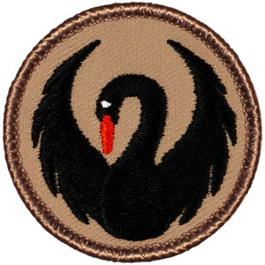 May include: A black embroidered patch with a black swan with a red beak on a tan background. The patch is surrounded by a brown stitched border.