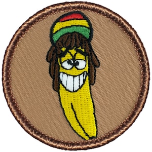 May include: A brown embroidered patch with a yellow banana wearing a red, green, and yellow hat with dreadlocks. The banana has a smiling face with white teeth.