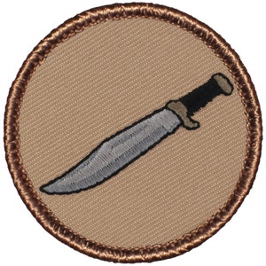 May include: A brown embroidered patch with a silver knife on a tan background.