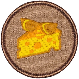 May include: A brown embroidered patch with a yellow and orange cheese wedge design. The cheese has holes and a textured surface.