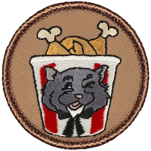 May include: Embroidered patch featuring a cartoon cat wearing a bow tie and peeking out of a red and white striped bucket of fried chicken.