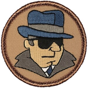 May include: Embroidered patch featuring a cartoon illustration of a person wearing a blue fedora, sunglasses, and a gray coat. The patch is circular and has a brown border.