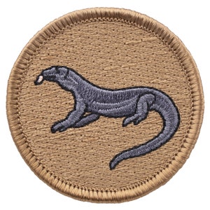 May include: A tan embroidered patch with a gray lizard design. The lizard is facing left and has a long tail.