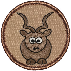 May include: A brown embroidered patch with a cartoon image of a brown antelope with large eyes and curled horns. The patch is circular and has a brown border.