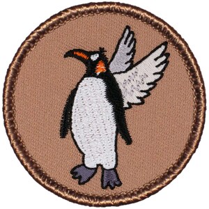 May include: A brown embroidered patch with a white penguin with black wings and a black beak. The penguin is standing on its feet with its wings spread out. The penguin has a small orange stripe on its head.
