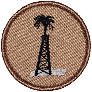May include: A brown embroidered patch with a black silhouette of an oil derrick and palm tree. The derrick is on a white platform.