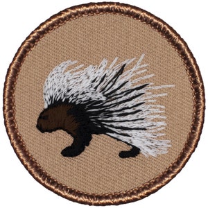 May include: A brown, black, and white embroidered patch of a porcupine with its quills raised. The patch is circular and has a brown border.