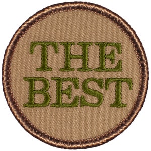May include: A round, brown embroidered patch with the words "THE BEST" in green lettering.