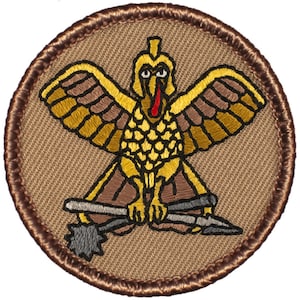 May include: A brown embroidered patch with a gold bird holding two weapons. The bird has a red beak and a yellow crest. The patch is surrounded by a brown border.