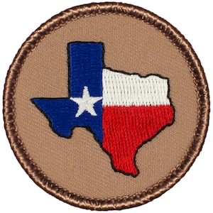 May include: A brown embroidered patch with a white outline of the state of Texas. The inside of the state is filled with the Texas flag colors of blue, white, and red.