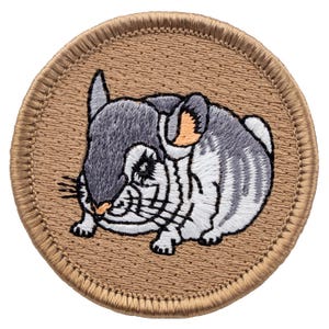 May include: A brown embroidered patch with a gray and white chinchilla on a tan background.
