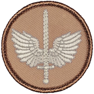 May include: A tan embroidered patch with a white sword with wings. The patch has a brown stitched border.