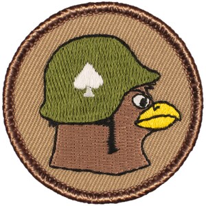 May include: A brown and yellow cartoon bird wearing a green military helmet with a white spade symbol. The bird is looking to the right. The image is on a tan background with a brown border.