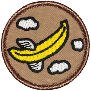 May include: A brown embroidered patch with a yellow banana with white wings flying through the air with white clouds.