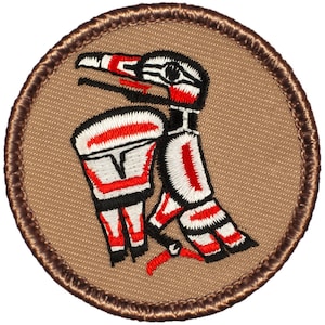 May include: A round, brown embroidered patch with a stylized red, white, and black bird design. The bird is facing right and has a long beak.