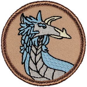 May include: Embroidered patch featuring a stylized dragon's head in profile. The dragon has light blue and gray details, with a tan background and a brown border. The patch is round and likely for clothing or accessories.