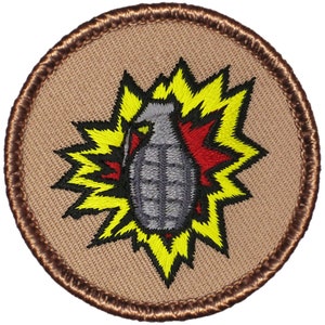 May include: A brown embroidered patch with a gray grenade exploding with yellow and red flames.