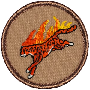 May include: A brown embroidered patch with a brown border. The patch features a red and orange tiger with flames coming from its back. The tiger is leaping forward.