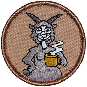 May include: Embroidered patch featuring a cartoon goat with horns, wearing a gray dress and holding a steaming cup of coffee. The patch is brown with a light brown background.