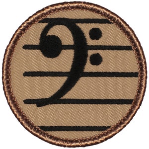 May include: A brown and black embroidered patch with a bass clef and treble clef on a brown background.