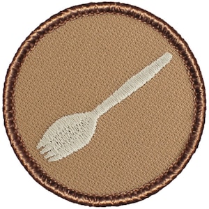 May include: A brown embroidered patch with a white fork design. The patch has a brown stitched border.