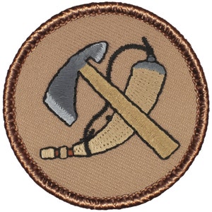 May include: Embroidered patch featuring a crossed axe and a canteen. The patch has a tan background with a brown border. The axe is gray and tan, and the canteen is tan with black detailing. The patch is circular.