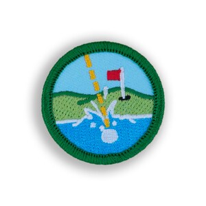 May include: A green embroidered patch with a white golf ball splashing into a blue body of water. A yellow dashed line leads to a red flag on a green golf course.