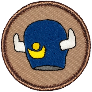 May include: A brown embroidered patch with a blue, white, and yellow cartoon character with horns. The character has a large blue head with a yellow and white design on the front.