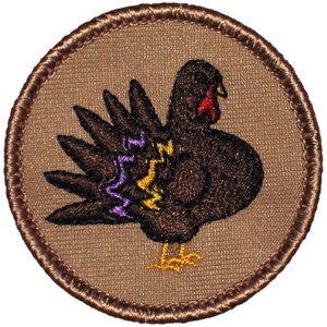 May include: A brown embroidered patch with a turkey design. The turkey is brown with a red wattle and yellow feet. The turkey's tail feathers are purple and yellow.